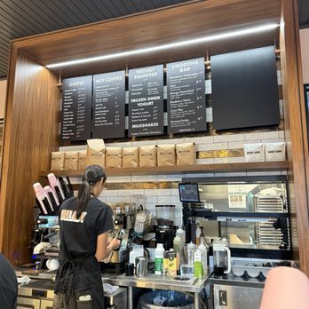 Bready Cafe - A barista is working behind a coffee counter at Bready Cafe, with menu boards above and coffee supplies around. - Bakeries Near Me - Toronto, Ontario