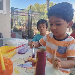 Milpitas Child Care & Learning Center - A child painting on a toilet paper roll.