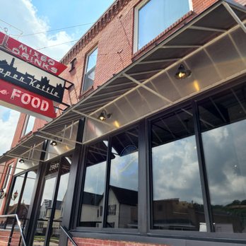 Copper Kettle - The image shows the storefront of Copper Kettle, featuring a sign with the business name and large glass windows reflecting the sky. - Burgers Near Me - Dubuque, Iowa