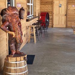 Outdoor seating w/ a crazy wooden statue.