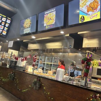 Spin Pollo - A restaurant counter with digital menu screens displaying food options, holiday decorations, and staff preparing orders. - Peruvian Near Me - Alexandria, Virginia