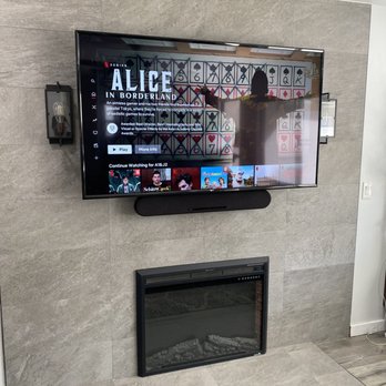 The Install Guys - Perfectly mounted 65-inch tv between two wall lights and above an electric fireplace - Home Theatre Installation Near Me