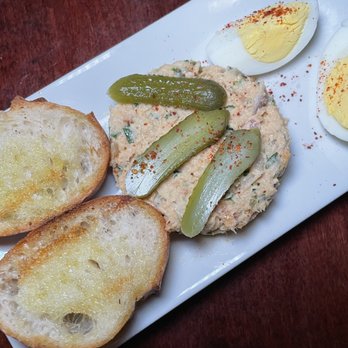 Tapas Teatro - Trouta Ahumada - A rectangular white plate holds toasted bread slices, deviled eggs, and a creamy spread topped with pickles and paprika, served at Tapas Teatro in Baltimore. - Tapas Bars Near Me - Baltimore, Maryland