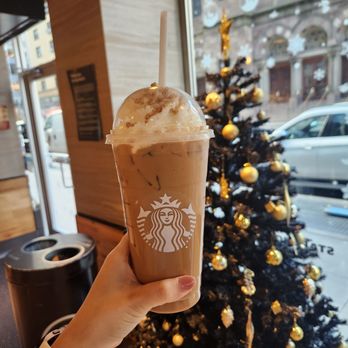 Starbucks - a person holding a cup of coffee in front of a christmas tree - Coffee & Tea Near Me - New York, New York