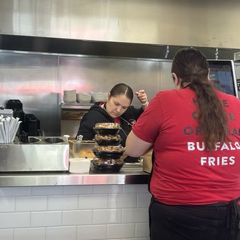 The Buffalo Spot - Manager in black touching her phone and hair while handling food with no gloves. - Chicken Wings Near Me - Mesa, Arizona