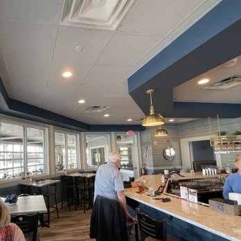 Dock House Restaurant - A view towards the south in the water-facing bar, with a wall of waterfront windows all along left and in another room ahead - Seafood Near Me - Chester, Maryland