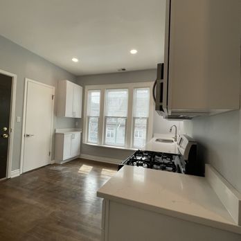 Chicago Reno - a kitchen with white cabinets and wood floors - General Contractors Near Me Chicago Reno - a kitchen with white cabinets and wood floors - General Contractors Near Me