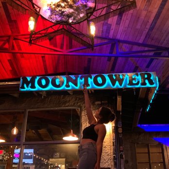 Moontower Saloon - a woman standing in front of a neon sign - Music Venues Near Me - Austin, Texas