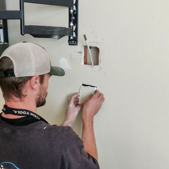 Klein Electric - Vince installing a new 4-outlet wall box behind a TV - Electricians Near Me