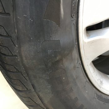 JD Tires - A car tire with a silver alloy wheel is shown, featuring dirt and some wear on the sidewall, likely in a garage or workshop setting. - Tires Near Me - Gilbert, Arizona