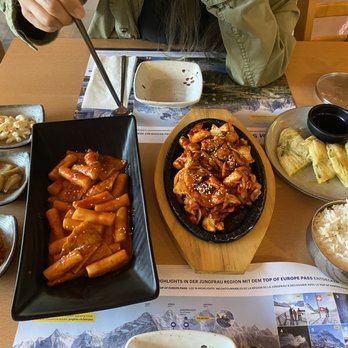 Restaurant Aare-Café - Banchan, tteokkbokki, Dak (chicken) Gochujang Bokkeum and pajeon (with leeks), with a bowl of white rice. - Hotels & Travel Near Me - Interlaken, BE Restaurant Aare-Café - Banchan, tteokkbokki, Dak (chicken) Gochujang Bokkeum and pajeon (with leeks), with a bowl of white rice. - Hotels & Travel Near Me - Interlaken, BE
