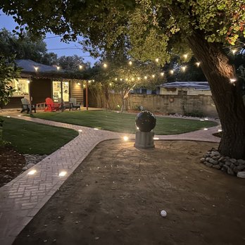 Green Ivy Maintenance - a patio with a fire hydrant and string lights - Landscaping Near Me