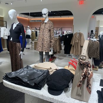 Mango - Mannequins dressed in leopard print outfits and accessories are displayed in a clothing store, with racks of apparel and fitting rooms visible in the background. - Women's Clothing Near Me - McLean, Virginia