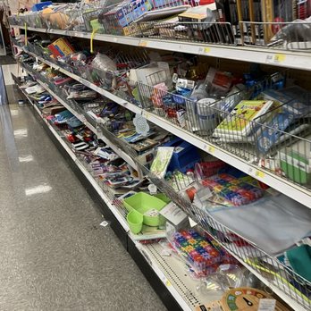 Target - Target appears to be in greater disarray every time we visit, but I was distracted by the long, slow checkout lines! - The image shows a store aisle with metal wire baskets on shelves, containing a variety of miscellaneous items such as toys, stationery, kitchenware, and craft supplies. The shelves are slightly disorganized, with items spilling over and scattered. The background reveals a retail environment with bright lighting, checkout counters, and other store fixtures. The floor is a polished, reflective surface typical of large retail stores. - Department Stores Near Me - Vauxhall, New Jersey