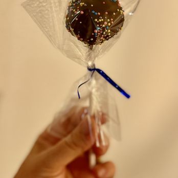 Bergeron’s Cafe - a hand holding a chocolate lollipop - Desserts Near Me Bergeron’s Cafe - a hand holding a chocolate lollipop - Desserts Near Me