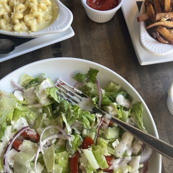 Modern Plate - Greek Salad & Mac N Cheese & Truffle Fries - A fresh salad with chopped lettuce, cherry tomatoes, red onions, and crumbled cheese, served on a white plate with a fork. - Cocktail Bars Near Me - Elmhurst, Illinois
