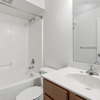 Plantation Oaks Apartments - A white bathroom with a toilet, sink, and mirror - Apartments Near Me - Savannah, Georgia Plantation Oaks Apartments - A white bathroom with a toilet, sink, and mirror - Apartments Near Me - Savannah, Georgia