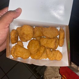 a hand holding a box of fried chicken nuggies a hand holding a box of fried chicken nuggies