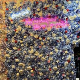 a man standing in front of a wall of flowers a man standing in front of a wall of flowers
