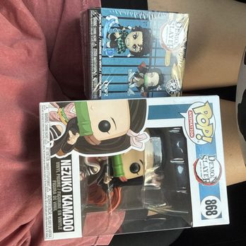 Kryptonite Character Store - Two more... this store is the best!! You can literally find anything - A Nezuko Kamado Funko Pop! figure in its box is resting on a person's lap inside a vehicle, with a Demon Slayer-themed box design. - Toy Stores Near Me - Pigeon Forge, Tennessee