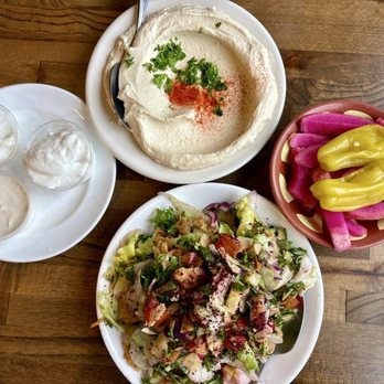 Al-Ameer - Hummus, salad - A meal featuring a fresh salad, creamy hummus garnished with herbs, and a bowl of colorful pickled vegetables on a wooden table. - Middle Eastern Near Me - Dearborn, Michigan