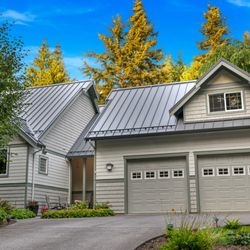 Mt Baker Roofing - A suburban home featuring a sleek, durable metal roof in a gray finish. The house showcases light gray siding with white trim.