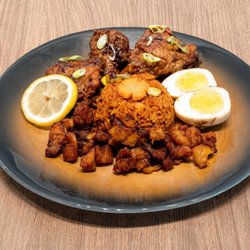 Masarap Cafe - Slow-Braised Goat Stew. Served with ripe plantain fritters, eggs, salad and jollof rice. Exceptional flavors
