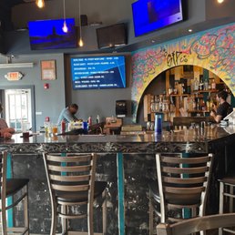 a bar with several chairs and a man at the bar