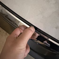 Foreign Motors Body Shop - Front grille moulding loose after clip was damaged and glued back on.