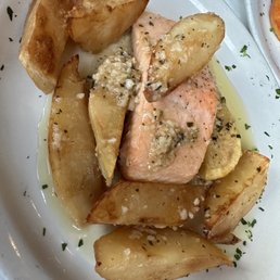 Salmone Vesuvio - Salmon fillet served with roasted potato wedges, topped with garlic and herbs, on a white plate.