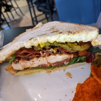 Jackson's Pit - My mouth waters just looking at the Buffalo Chicken BLT avec jalapeños, because everything is better with jalapeños! - A sandwich featuring grilled chicken, pickles, lettuce, tomato, and bacon on toasted bread, served on a plate with a side of fried food. - Burgers Near Me - Negaunee, Michigan
