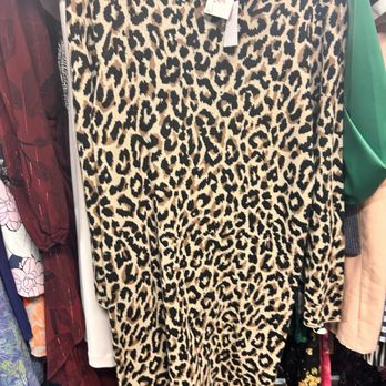 Lodi Junction - J. Crew - A leopard print dress with a beige background and black spots is displayed on a hanger in a thrift store, surrounded by other clothing items. - Thrift Stores Near Me - Lodi, California