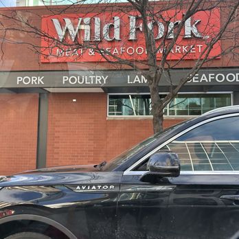 Wild Fork - Outside - Wild Fork Meat & Seafood Market storefront with signage indicating various meat categories, and a parked black vehicle in the foreground. - Meat Shops Near Me - Chicago, Illinois