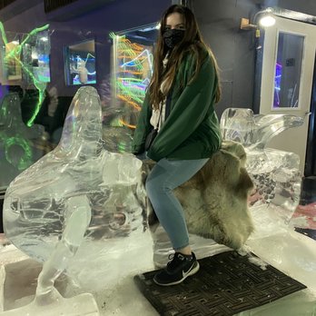 Fairbanks Ice Museum - This is me sitting on an ice sculpture of a snowmobile. In the back, you can sort of see the slide which we were allowed to slide down. - Museums Near Me - Fairbanks, Alaska