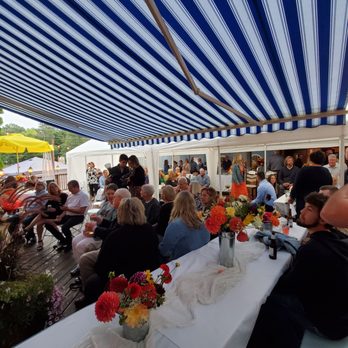 The Wheelhouse - a group of people sitting at a table under a blue and white awning - Pizza Near Me - Waupaca, Wisconsin The Wheelhouse - a group of people sitting at a table under a blue and white awning - Pizza Near Me - Waupaca, Wisconsin