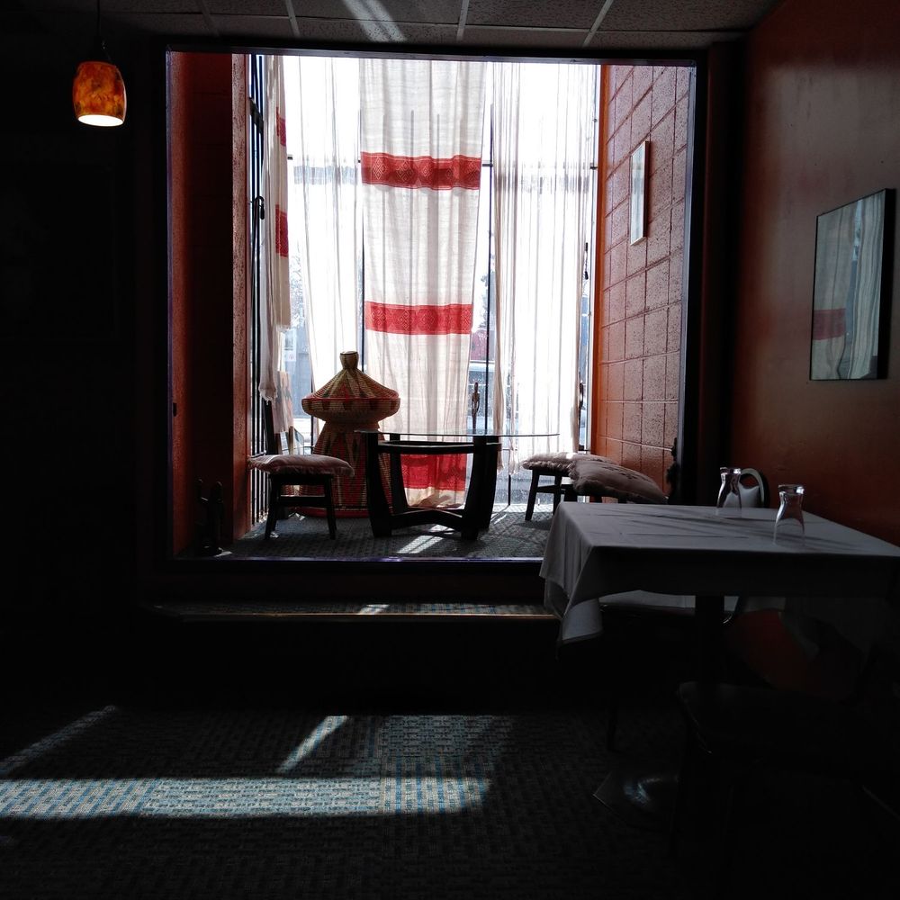 Africana Cafe - a man sitting at a table in front of a window - Ethiopian Near Me - Denver, Colorado