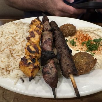 Al-Ameer - A large white plate holds rice, grilled skewers of meat, hummus garnished with parsley, and falafel balls, served in a Middle Eastern restaurant. - Middle Eastern Near Me - Dearborn, Michigan