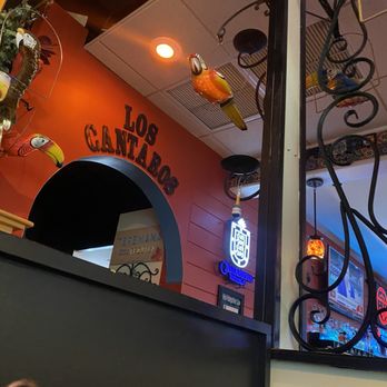 Los Cantaros - Los cantaros - The image shows part of the interior of Los Cantaros, a Mexican restaurant, with decorative glass birds hanging from the ceiling and a neon sign on the wall. - Mexican Near Me - Hampton, New Hampshire