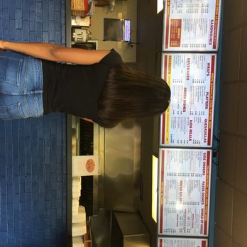 Hilltop Carry Out - a woman standing in front of a menu - Pizza Near Me - Glen Burnie, Maryland Hilltop Carry Out - a woman standing in front of a menu - Pizza Near Me - Glen Burnie, Maryland