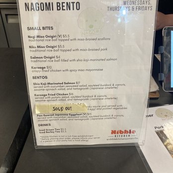 Nibble Kitchen - Nagomi Bento Menu - Menu board for Nagomi Bento at Nibble Kitchen in Somerville, MA, displaying options for small bites such as Negi Miso Onigiri, Niku Miso Onigiri, Salmon Onigiri, and Karaage, along with bento options like Shio Koji-Marinated Salmon, Karaage Fried Chicken, and Pan-Seared Japanese Eggplant, which is marked as sold out. The menu includes prices, descriptions, and notes about the restaurant's operating days and food allergies. - Brazilian Near Me - Somerville, Massachusetts