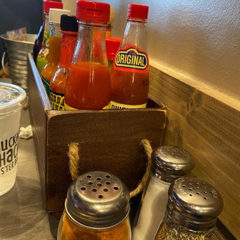 Shuckin' Shack Oyster Bar - Table Condiments. Old Bay chilling out and bunch of hot sauces - Seafood Near Me - Ocala, Florida