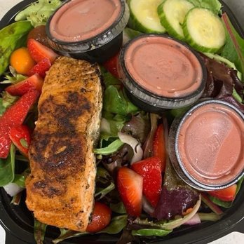 Simone's Kitchen ATL - Strawberry Salmon Salad, no tomatoes - Mixed greens salad with grilled salmon, sliced cucumbers, strawberries, and three small containers of salad dressing. - Food Trucks Near Me