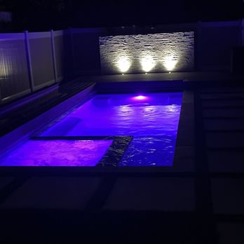NA Design Builders - Pool and spa at night with multicolored LED lights and accent wall - General Contractors Near Me - West Hollywood, California