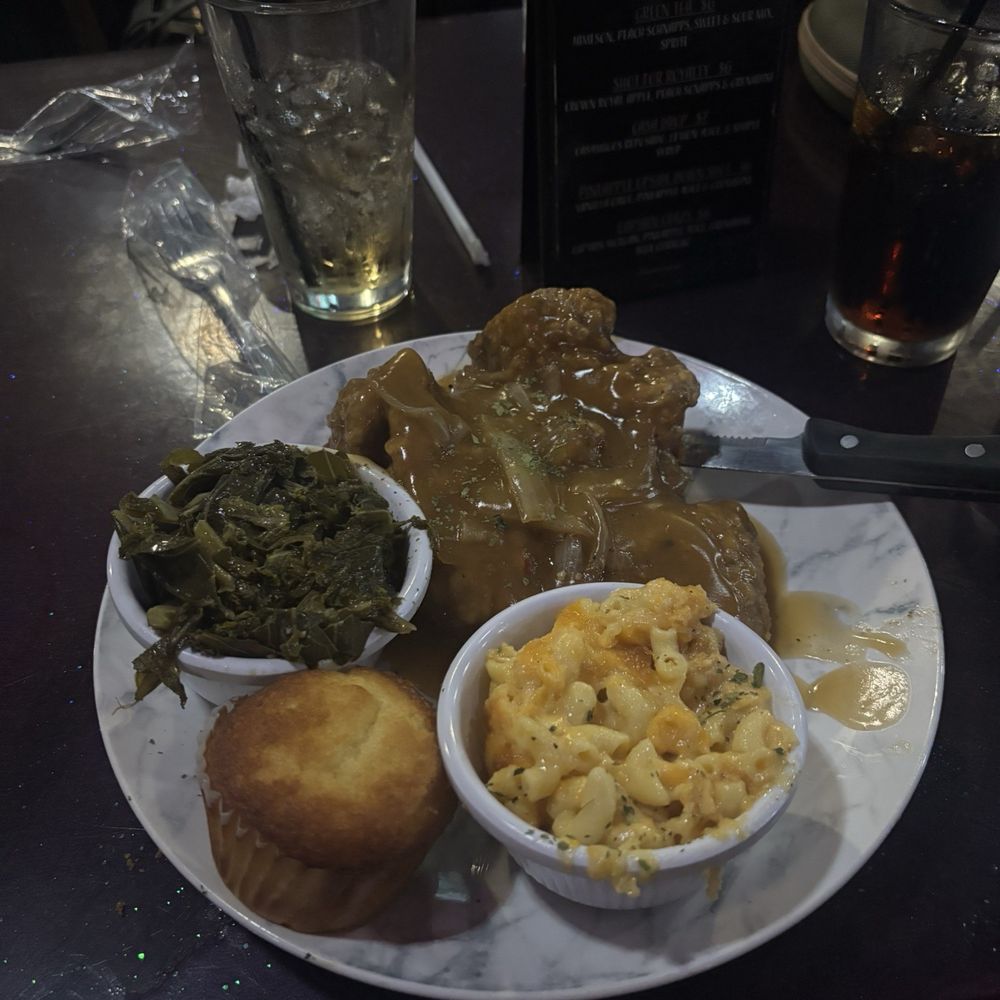 Smothered pork chop with greens, Mac & cheese, and cornbread