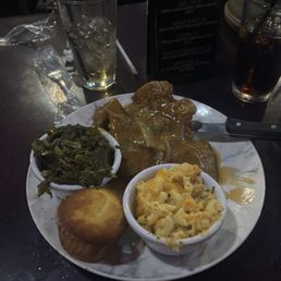 Smothered pork chop with greens, Mac & cheese, and cornbread