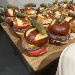 Tres Bien - Angus beef sliders animal style with cheddar and garnished with a pickle on pretzel buns