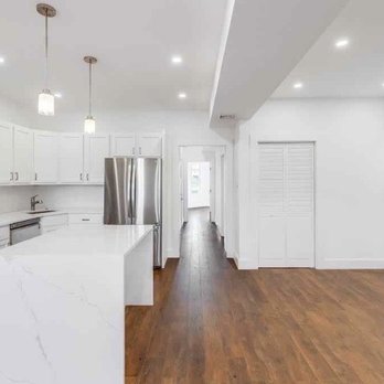 Ecoblok Contractor - a kitchen with white cabinets and stainless steel appliances - General Contractors Near Me