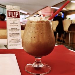 a glass of milkshake with whipped cream and sprinkles