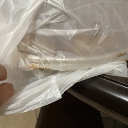 a person holding a sandwich wrapped in plastic a person holding a sandwich wrapped in plastic