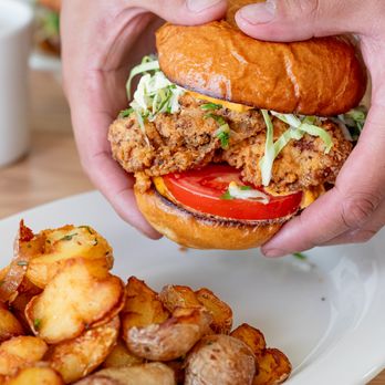 Eats - a person holding a sandwich over a plate of potatoes - American Near Me - San Francisco, California Eats - a person holding a sandwich over a plate of potatoes - American Near Me - San Francisco, California